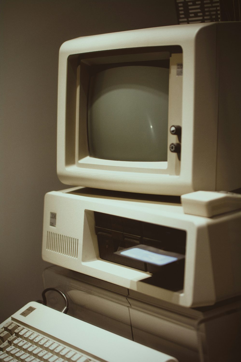 A vintage IBM personal computer with a floppy disk in the drive